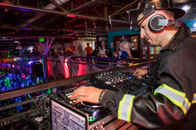 Firefighter DJ works the decks above a glowing dancefloor at Denver's Coloween Halloween party