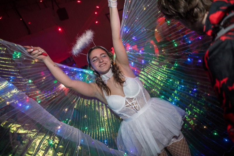 Angel in a halo throwing her light-up wings wide mid-dance at Coloween 2021 in Colorado