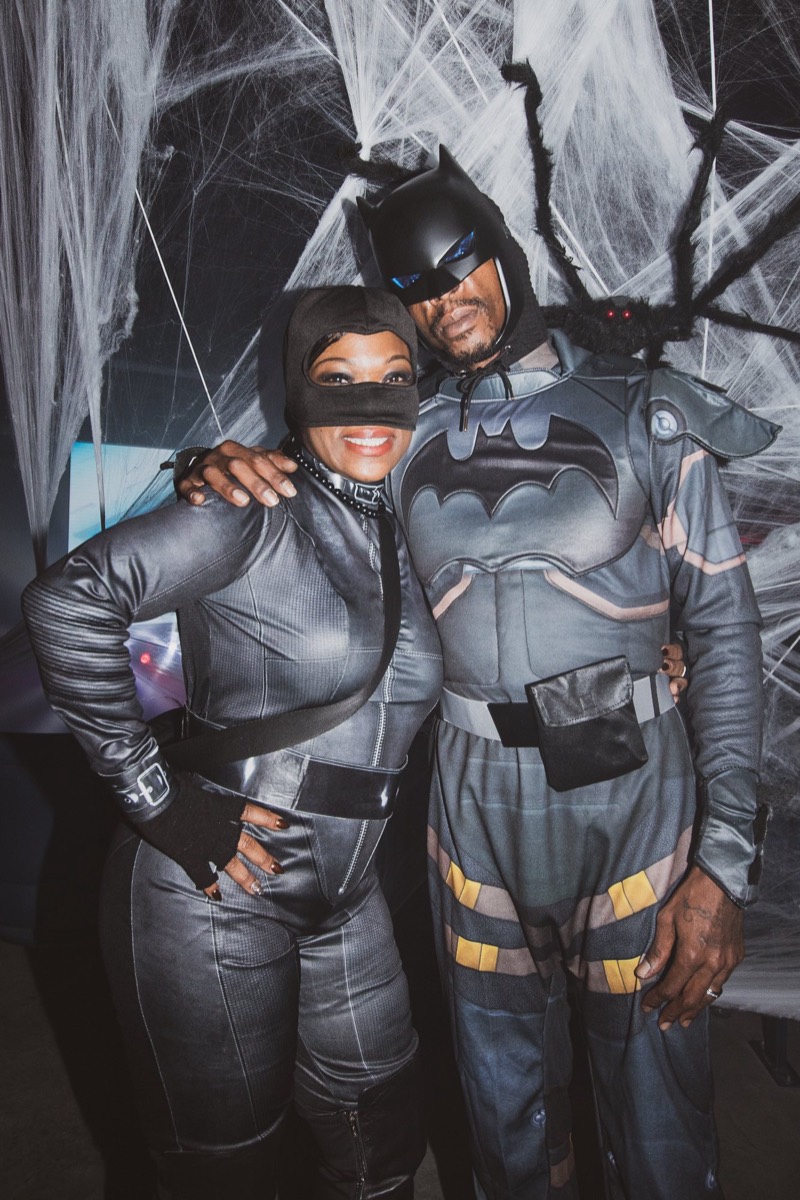 Batman and Catwoman pose in front of a giant spiderweb at Coloween's Halloween costume party
