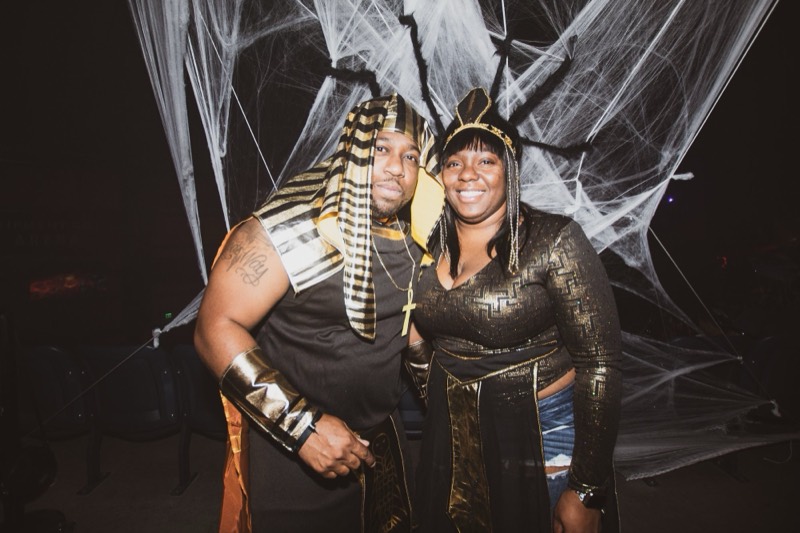 Pharaoh and Cleopatra pose arm in arm before the spiderweb wall at the Coloween costume contest in Denver
