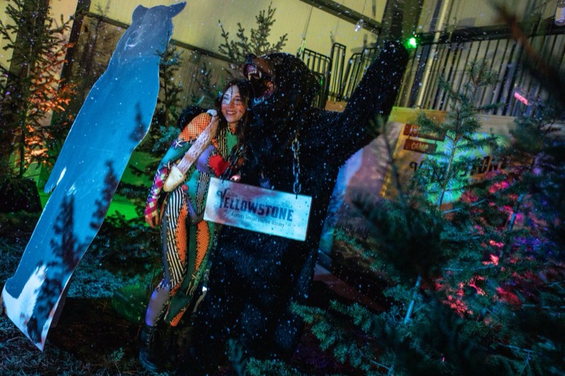 Rag-doll costume hugs a growling bear in a snowy pine camp at Coloween's Halloween costume party
