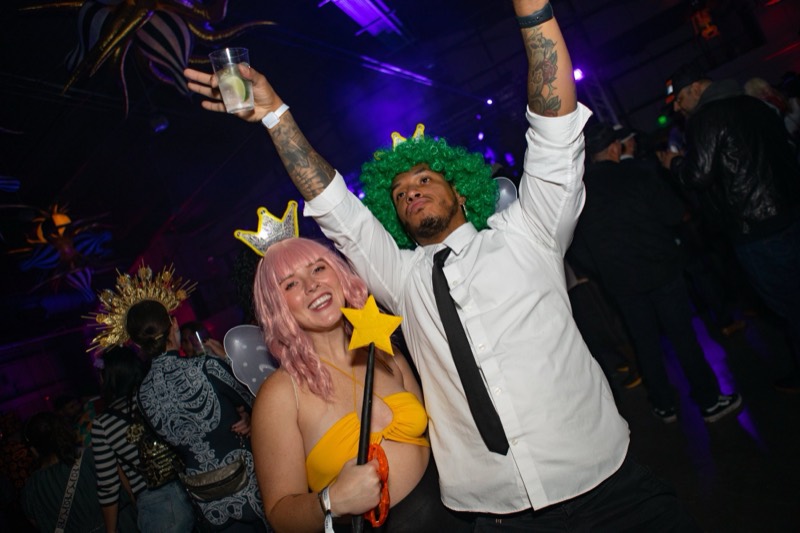 Fairy with star wand and green-wigged king cheering mid-dance at Coloween, Denver's 21+ Halloween party