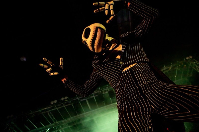 Jack Skellington stilt walker looms over the stage in green haze on the dance floor at Coloween 2023