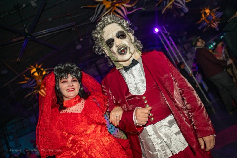 Beetlejuice groom arm in arm with his red-veiled bride at Coloween 2023 in Colorado