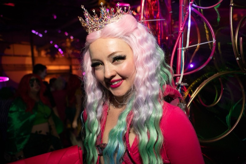 Crystal crown and pastel mermaid waves lit by pink neon at the adults-only Coloween Halloween event