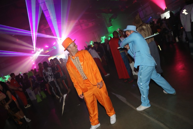 Orange and blue tuxedos grinning beneath the laser canopy at Coloween — Denver Halloween nightlife