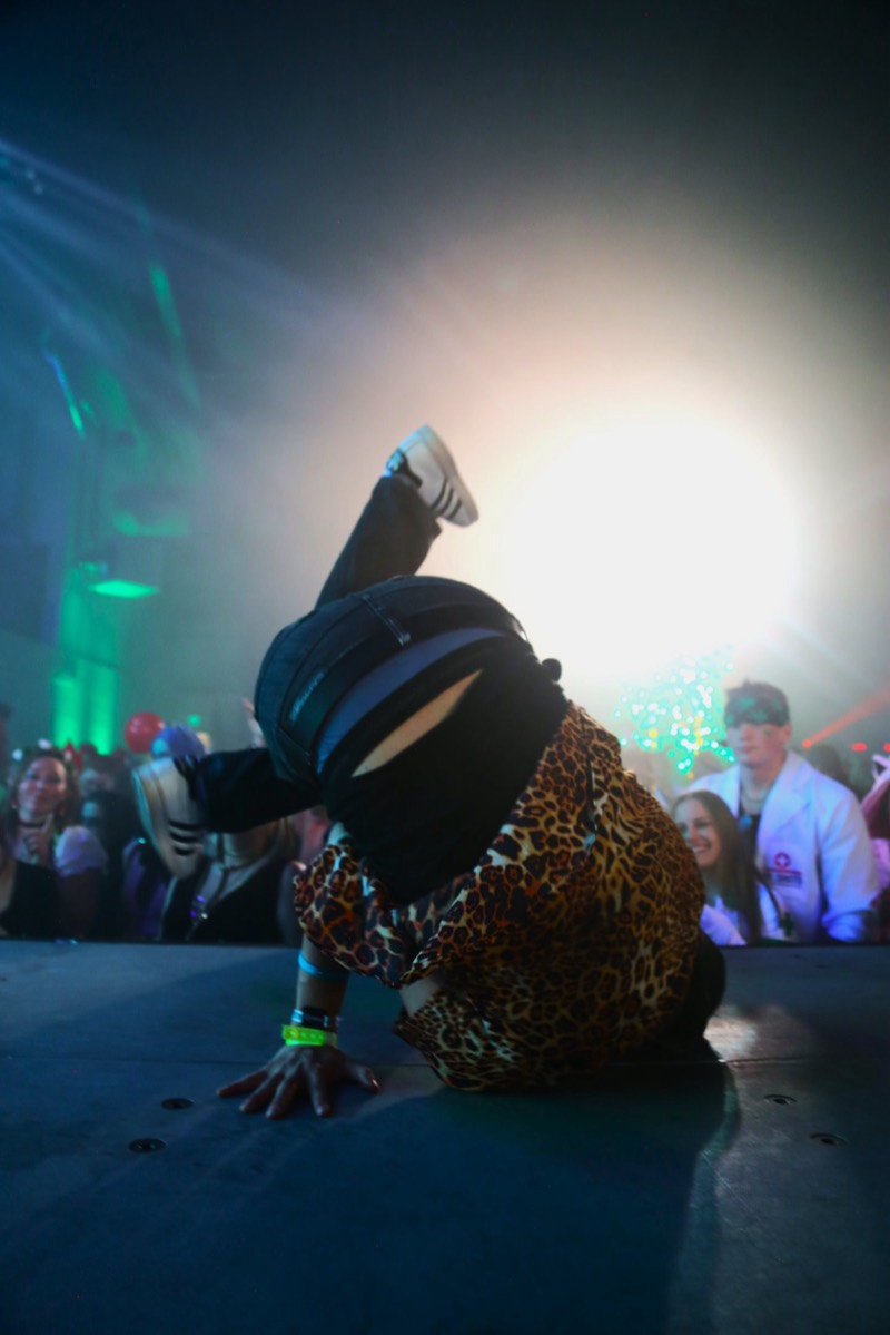 Leopard-print breakdancer frozen upside down on stage in the spotlight