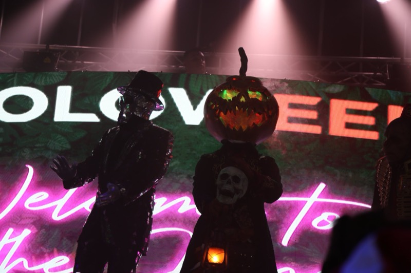 Mirror-suit dancer and glowing pumpkin-head greet the crowd on stage at Coloween — Denver Halloween nightlife