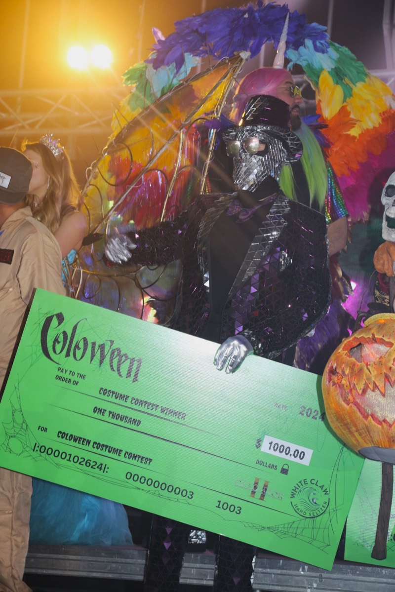 Mirror-tiled suit accepting the thousand-dollar costume contest check on stage at Colorado's biggest adult Halloween party