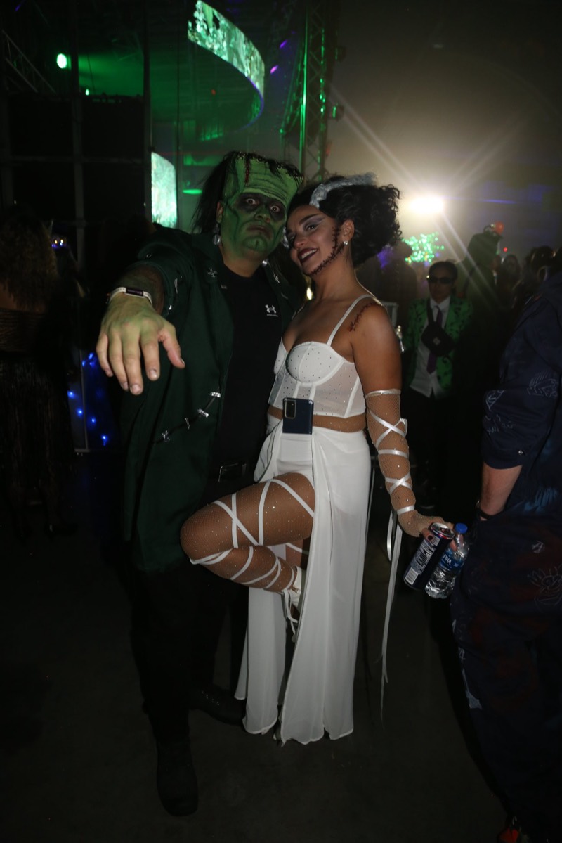 Frankenstein reaches for the camera beside his glittering bride on the dance floor at Coloween 2024