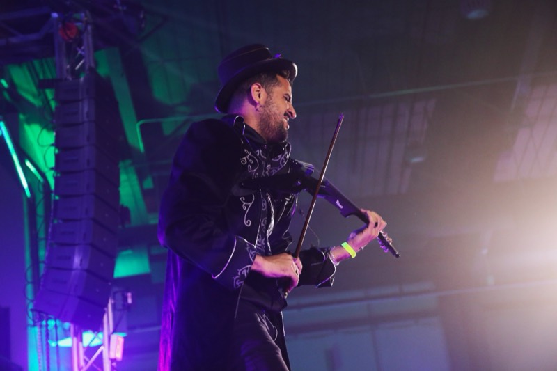Electric violinist in a velvet coat shredding above the stage lights at Colorado's biggest adult Halloween party
