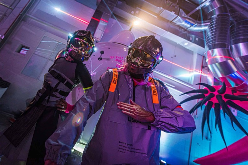 Two astronauts pose in a rocket set with pink alien tentacles at Coloween, Denver's 21+ Halloween party