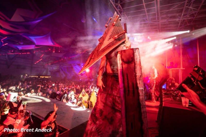 Pyramid-head figure drags a great sword through red stage fog at the Coloween costume contest in Denver