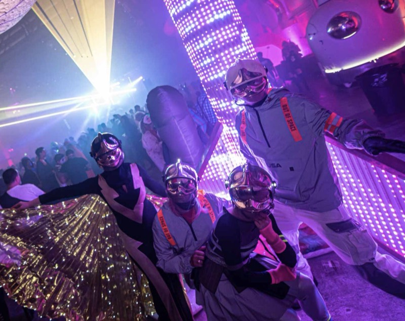 Chrome-helmet space crew posed against a glowing pixel tower at Coloween — Denver Halloween nightlife