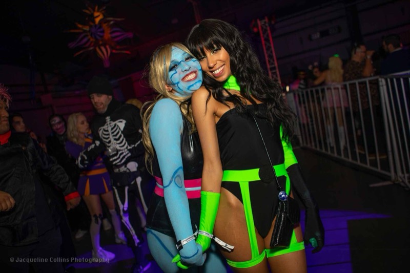 Blue body paint meets a neon green villain in a laughing hug at Colorado's biggest adult Halloween party