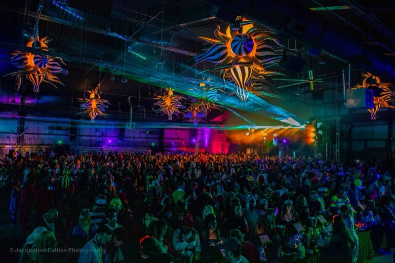 Striped inflatable creatures and lasers over a packed dance floor on the dance floor at Coloween