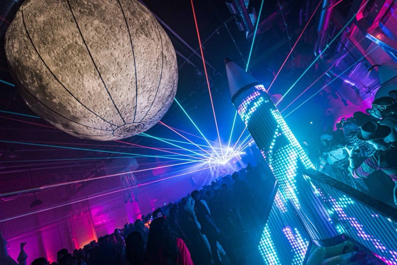Giant moon balloon and LED rocket over a packed dance floor at Coloween in Colorado