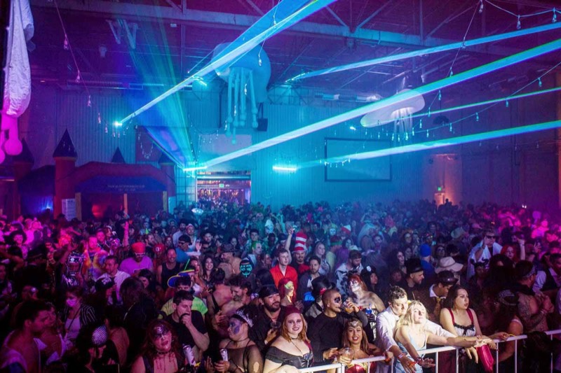 Cyan lasers and jellyfish inflatables over a sea of costumes at Denver's Coloween Halloween party