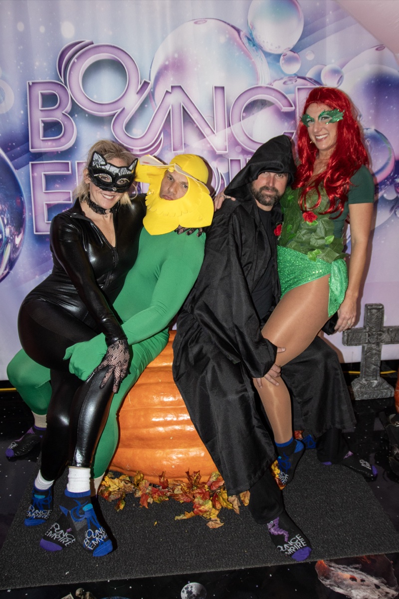 Catwoman, a corn cob, a reaper, and Poison Ivy pile onto the pumpkin backdrop at the adults-only Coloween Halloween event