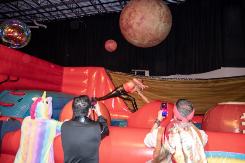 Mid-flight onto the red stunt bag, friends filming the landing at the Coloween costume contest in Denver